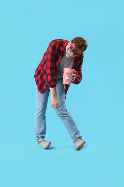 Cadılar Bayramı için giyinmiş genç adam mavi arka planda patlamış mısırla