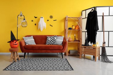 Cadılar Bayramı için dekore edilmiş oturma odasının içinde kanepe ve raf ünitesi var.