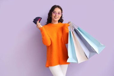 Kredi kartları ve eflatun çantalarıyla genç Asyalı kadın.