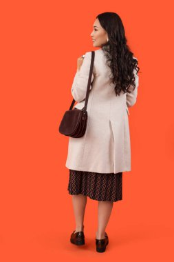 Kırmızı arka planda sonbahar kıyafetleri içinde şık genç Asyalı kadın.