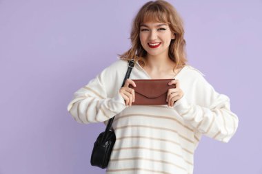 Leylak arka planda cüzdanı olan genç bir kadın.