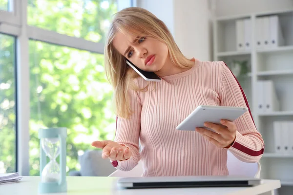 Young businesswoman with tablet computer working under deadline in office