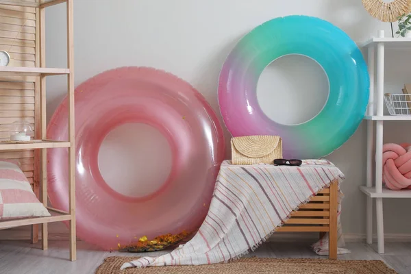 Inflatable rings, female bag and sunglasses near light wall in room
