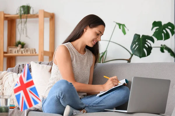 Young woman with laptop learning English language online at home