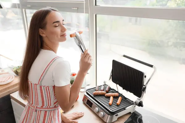 Beautiful Young Woman Cooking Delicious Sausages Modern Electric Grill Kitchen — Stock Photo, Image