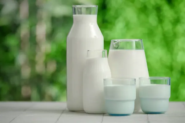屋外の白いタイルのテーブルの新鮮なミルクのガラスそしてびん — ストック写真