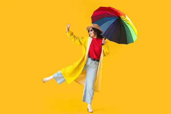 穿着黄色背景雨伞的时髦年轻亚洲女人 — 图库照片