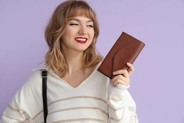 Young woman with wallet on lilac background