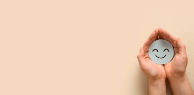 Bej arka planda gülümseyen kağıtları tutan eller ve metin için yer. Dünya Akıl Sağlığı Günü