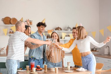 Şampanyalı bir grup genç arkadaş mutfakta doğum gününü kutluyorlar.