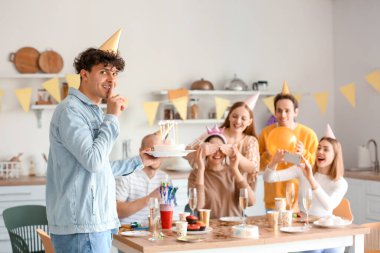 Genç adam partideki arkadaşına doğum günü pastası getiriyor.