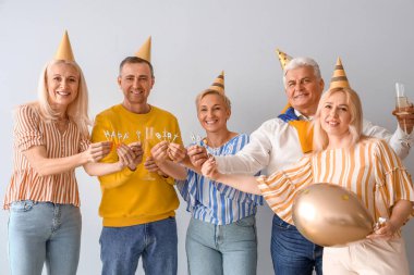 Mumları olan olgun insanlar aydınlık arka planda doğum gününü kutluyor.