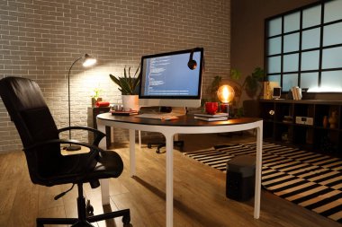 Karanlık ofisin içinde bilgisayarı olan programcının çalışma yeri