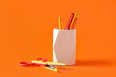 Renk arkaplanında kalem ve makas tutan