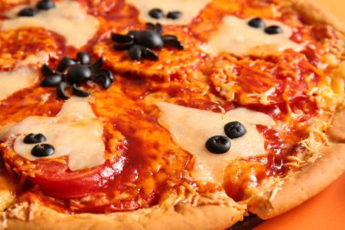 Cadılar Bayramı için turuncu arka planda lezzetli bir pizza.