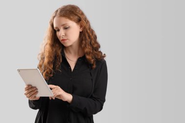 Arka planda tablet bilgisayarı olan genç bir iş kadını.