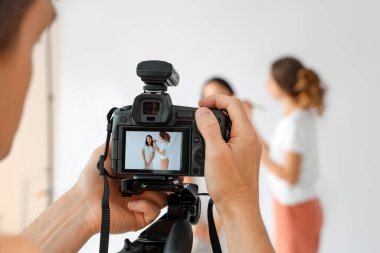 Stüdyoda genç Asyalı bir kadının fotoğrafını çeken erkek fotoğrafçı.