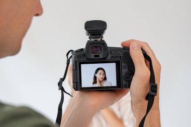 Stüdyoda genç Asyalı bir kadının fotoğrafını çeken erkek fotoğrafçı.