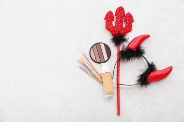 Makyaj fırçaları, fondöten şişesi, göz farı ve cadılar bayramı kutlaması için hafif arka planda aksesuarlar.