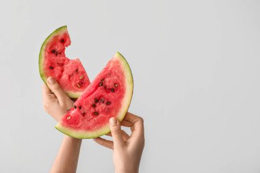 Beyaz arka planda olgun karpuz dilimleriyle kadın elleri