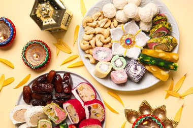 Mumlu Diya lambaları ve bej arka planda farklı ikramlardan oluşan tabaklar. Divaly kutlaması