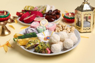 Mumlu Diya lambaları ve bej arka planda farklı ikramlardan oluşan tabaklar. Divaly kutlaması