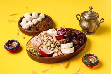 Mumlu Diya lambası, şeker kasesi ve sarı arka planda farklı tabaklar. Divaly kutlaması