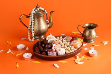 Mumlu çaydanlık, boncuklar ve turuncu arka planda farklı ikramlar. Divaly kutlaması