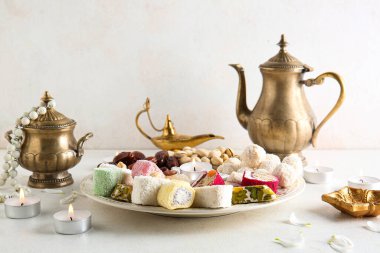 Mumlu Diya lambaları, çaydanlık ve beyaz masadaki farklı ikramlar. Divaly kutlaması