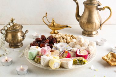 Mumlu Diya lambaları, çaydanlık ve beyaz masadaki farklı ikramlar. Divaly kutlaması