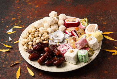 Mumlu Diya lambası ve grunge kahverengi arka planda farklı ikramlardan oluşan bir tabak. Divaly kutlaması