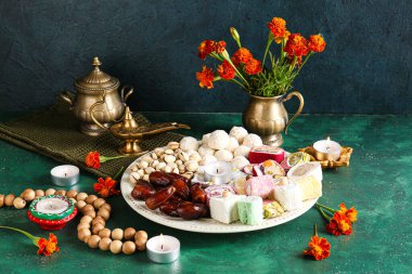 Mumlar, boncuklar, kadife çiçekleri ve grunge yeşil arka planda farklı tabaklar bulunan Diya lambaları. Divaly kutlaması