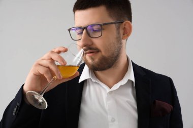 Gri arka planda şarap tatan genç şarap garsonu, yakın plan.