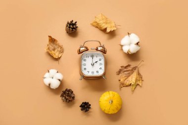 Düşen yapraklı çalar saat, köknar kozalakları, balkabağı ve bej arka planda pamuk çiçekleri