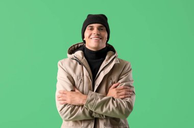 Yeşil arka planda, kışlık elbiseli genç adam.