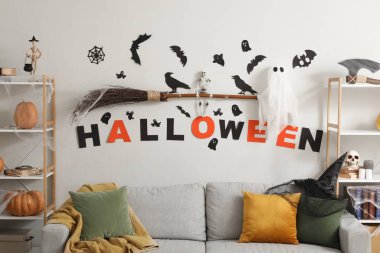 Cadılar Bayramı için dekore edilmiş oturma odasının içi kanepe ve raf üniteleriyle dolu.