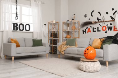 Cadılar Bayramı için dekore edilmiş oturma odasının içi kanepeler ve raf üniteleriyle dolu.