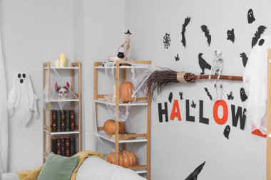 Cadılar Bayramı için dekore edilmiş aydınlık oturma odasının içi raf üniteleriyle dolu.