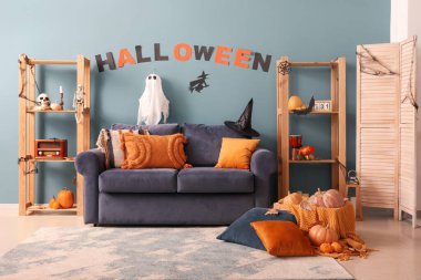 Cadılar Bayramı için dekore edilmiş oturma odasının içi kanepe ve raf üniteleriyle dolu.