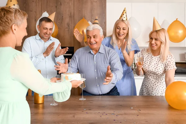 お祝いのケーキを持つ成熟した人々キッチンで誕生日 — ストック写真