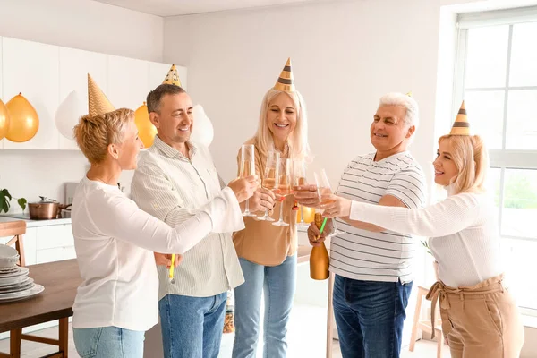 Mature people drinking champagne at Birthday party in kitchen