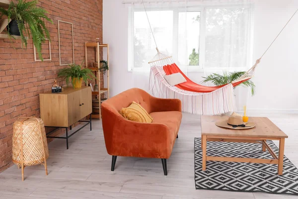 Interior of stylish living room with brown sofa, hammock and coffee table