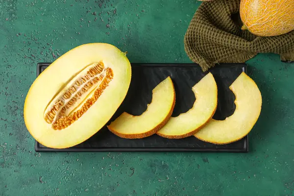 Board with pieces of sweet melon on green table