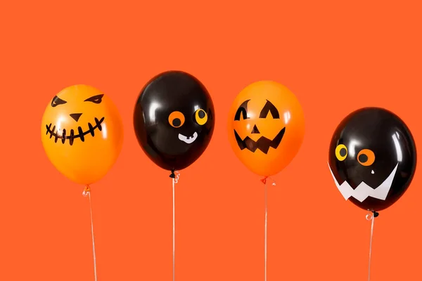 Different creepy Halloween balloons on orange background