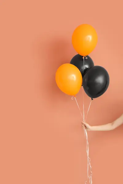 Female hand with different Halloween balloons on color background