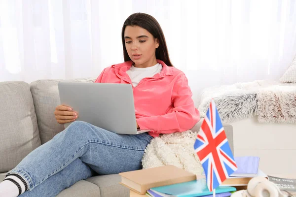 Young woman with laptop learning English language online at home