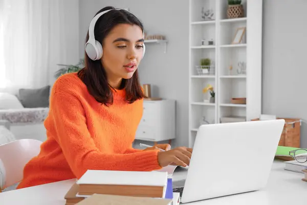Young woman in headphones learning English language online at home