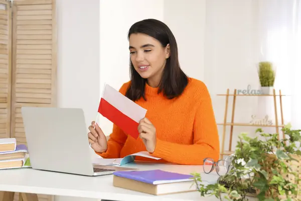 Young woman with flag of Poland learning language online at home