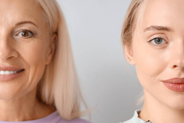 Счастливая молодая красивая женщина с матерью на сером фоне