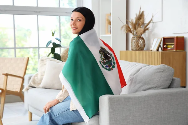 stock image Young woman with Mexican flag sitting on sofa at home